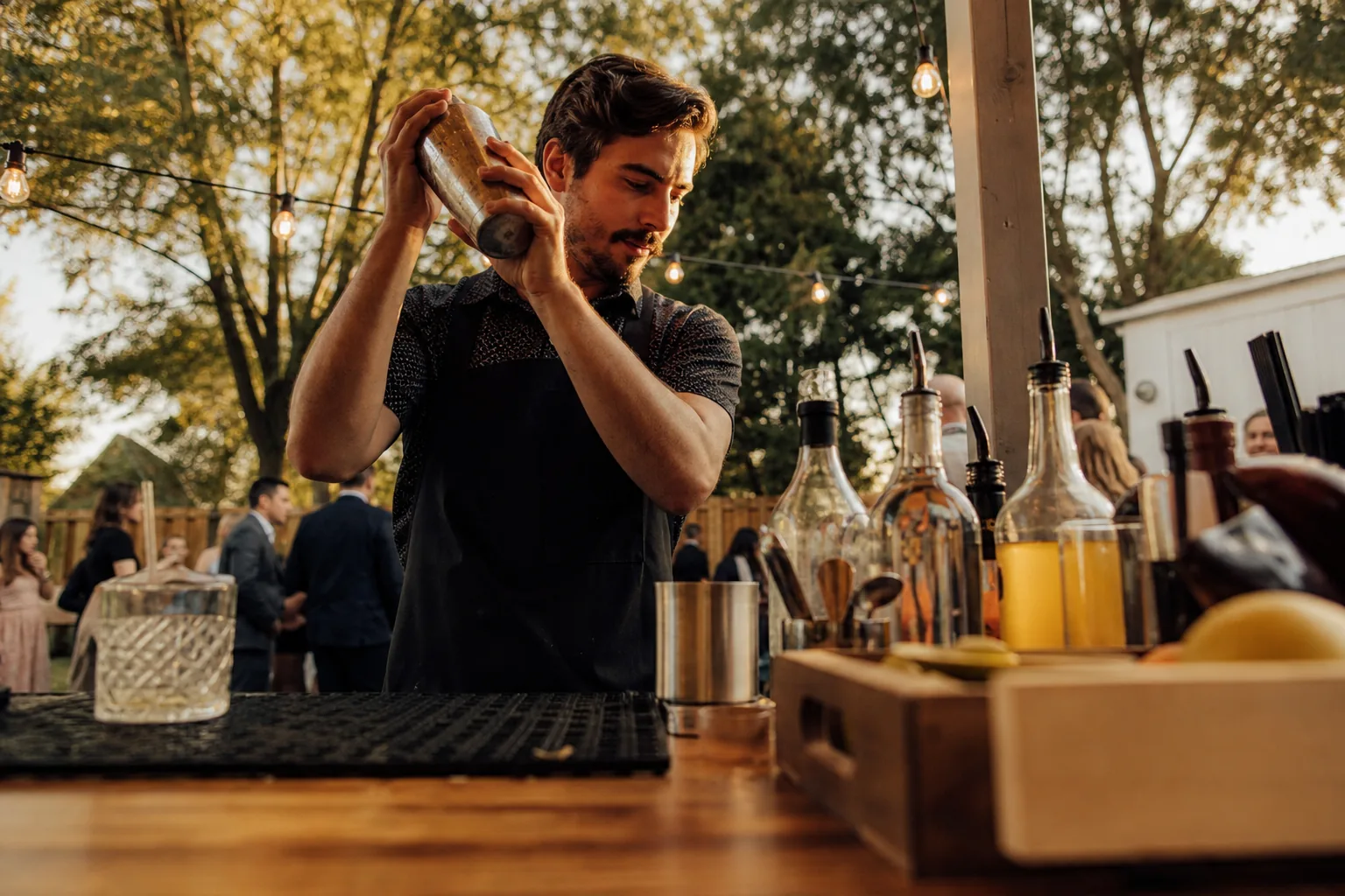 Mobile bartender shaking a cocktail at a backyard wedding bar