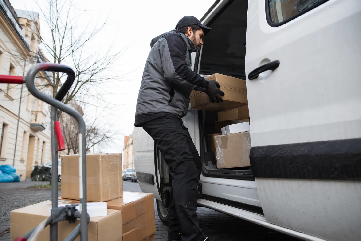 Delivery driver loading parcels into a small van